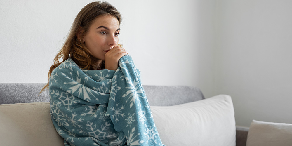 Woman sitting on couch with blanket